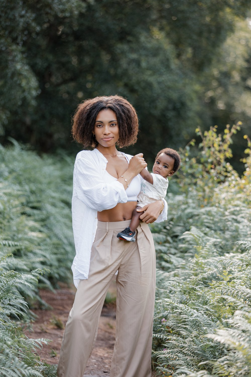 A young mother holding her baby son while on a walk through a forest in Leeds