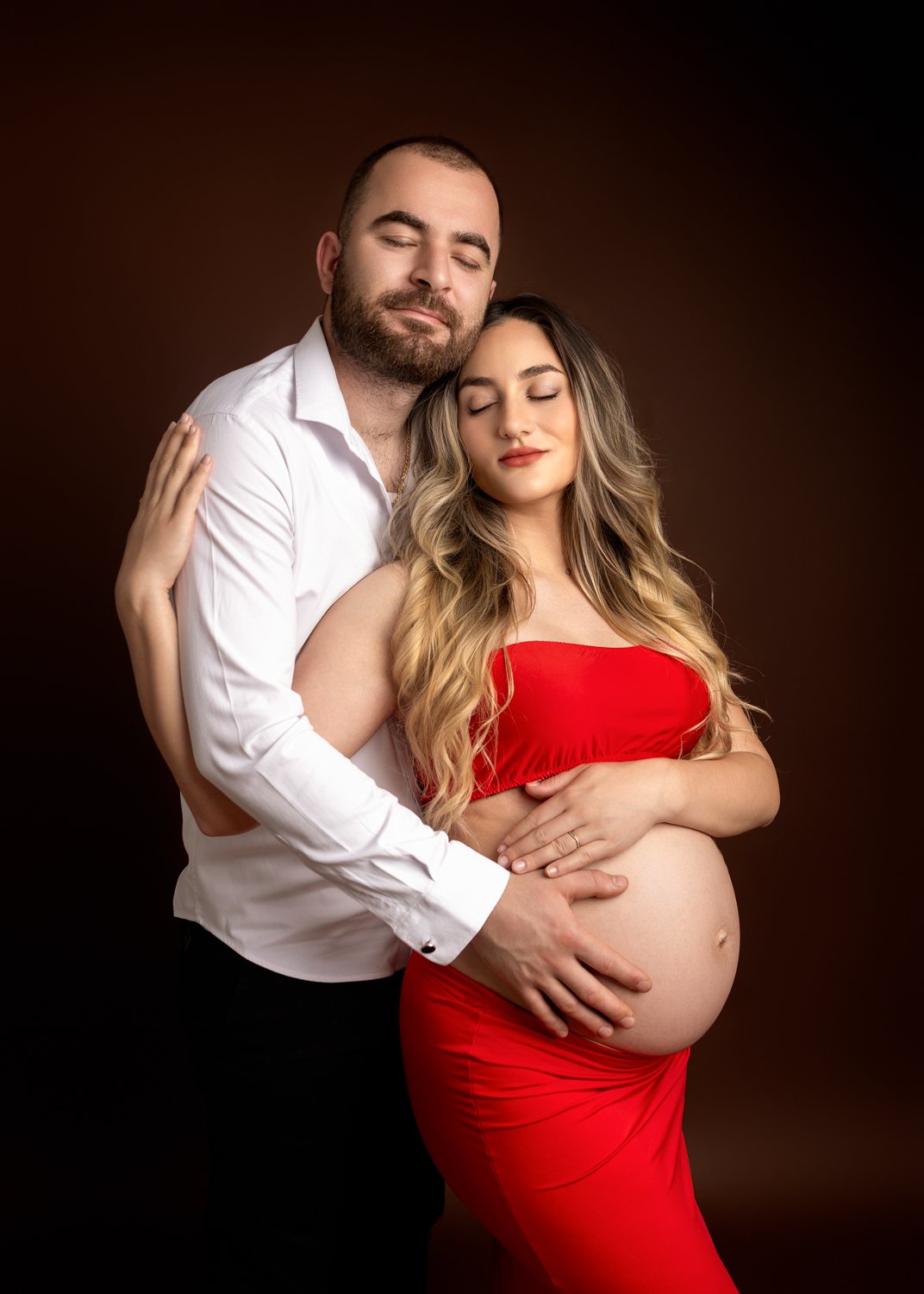A pregnant woman in a red top and skirt posing for a photo during their maternity photoshoot in Leeds