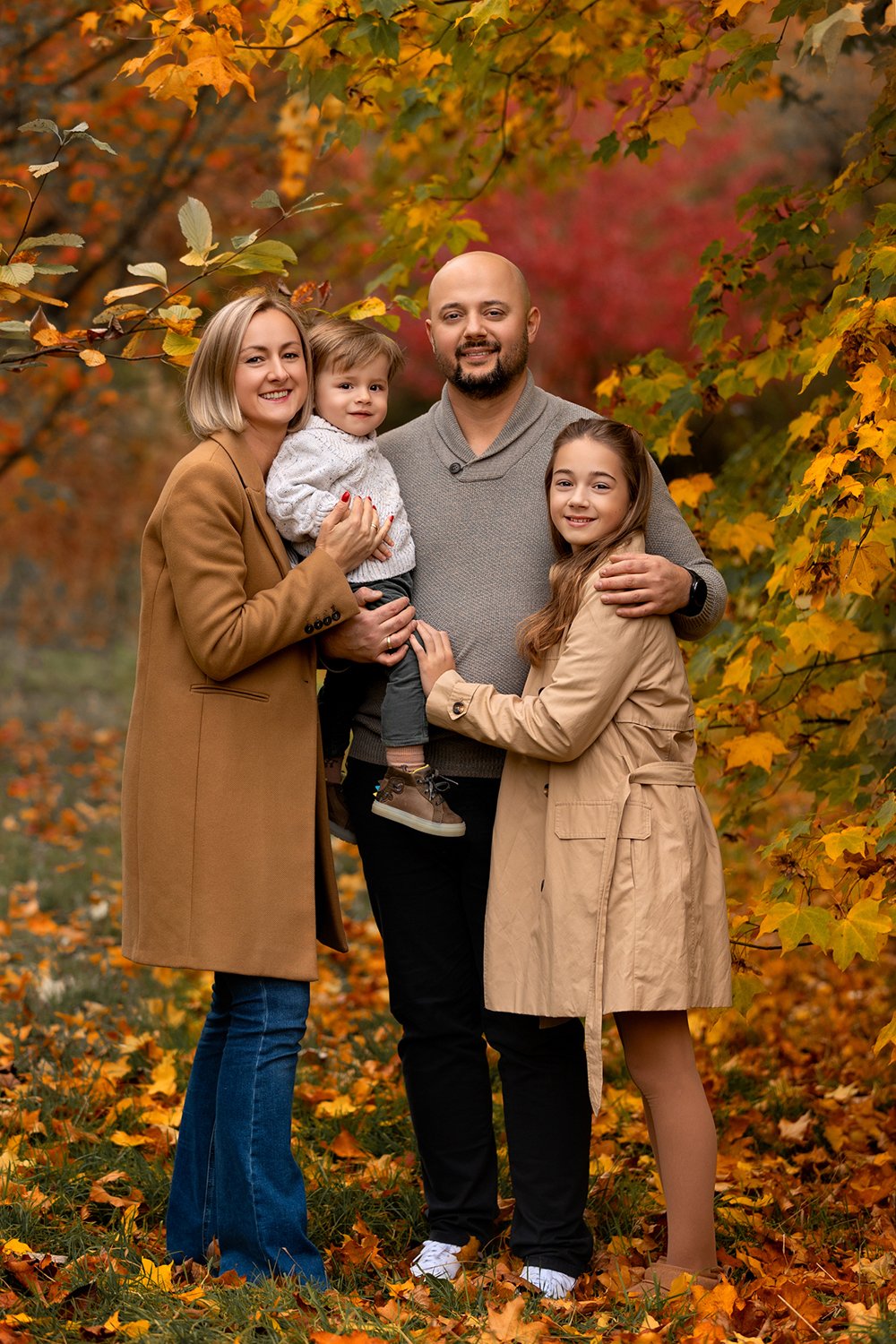 A family of 4 in a autumn park in Leeds, surrounded by autumn colours