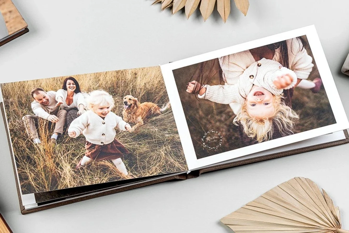 Open photo album displaying pictures of children playing outdoors in a field with tall grass, with a dog and a woman also in the photos.