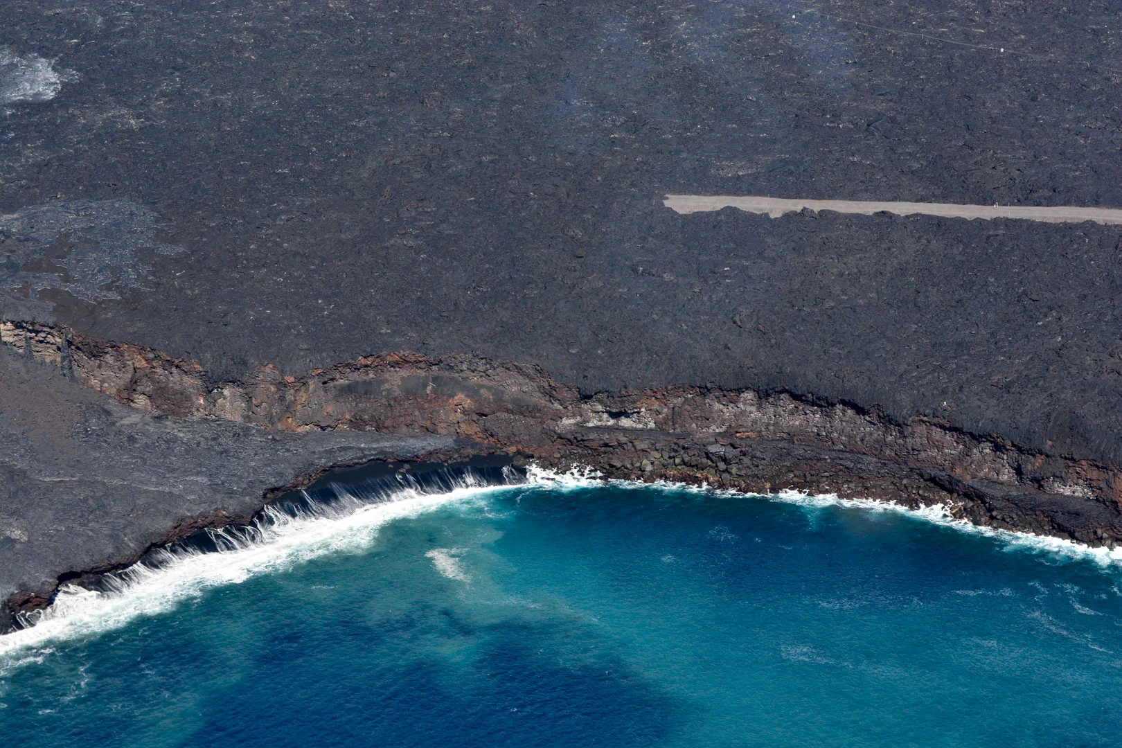 A close-up of the lava entering the ocean as well as a road that was blocked off by active lava flow