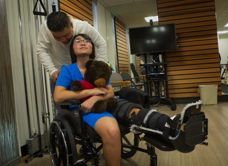 Phuong Dinh’s father, Hiep Dinh, prepares to take her back to her room after a news conference at the Keiro Northwest rehabilitation facility in Seattle on Wednesday, Dec. 2, 2015. (Ellen M. Banner/The Seattle Times)