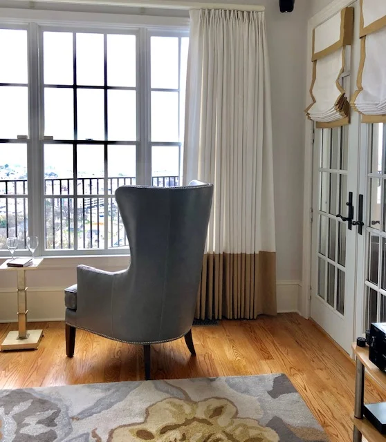 Did you know you can combine window treatment styles in the same room? Here we used curtain panels on a traverse rod that spans the entire width of this wall of windows in combination with Roman shades on the French doors. These window treatments share the same fabrics for continuity. I love how crisp these treatments feel.