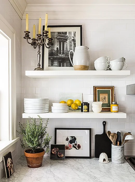 An eclectic mix of framed art was tucked into these open shelves and mixed with more utilitarian elements - including a big pot of rosemary! Image from OneKingsLane.