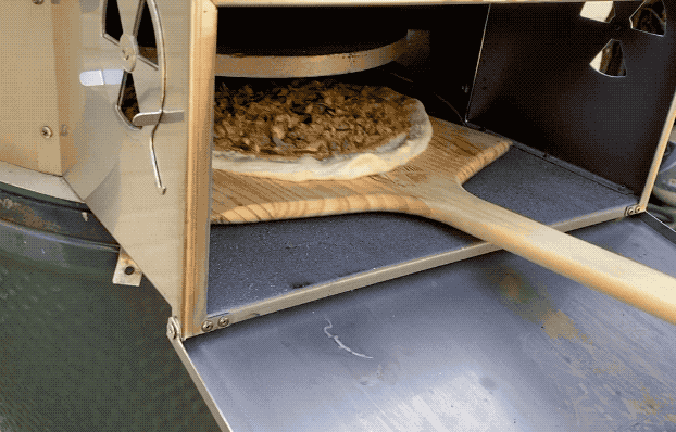 Loading a pizza with a wooden peel