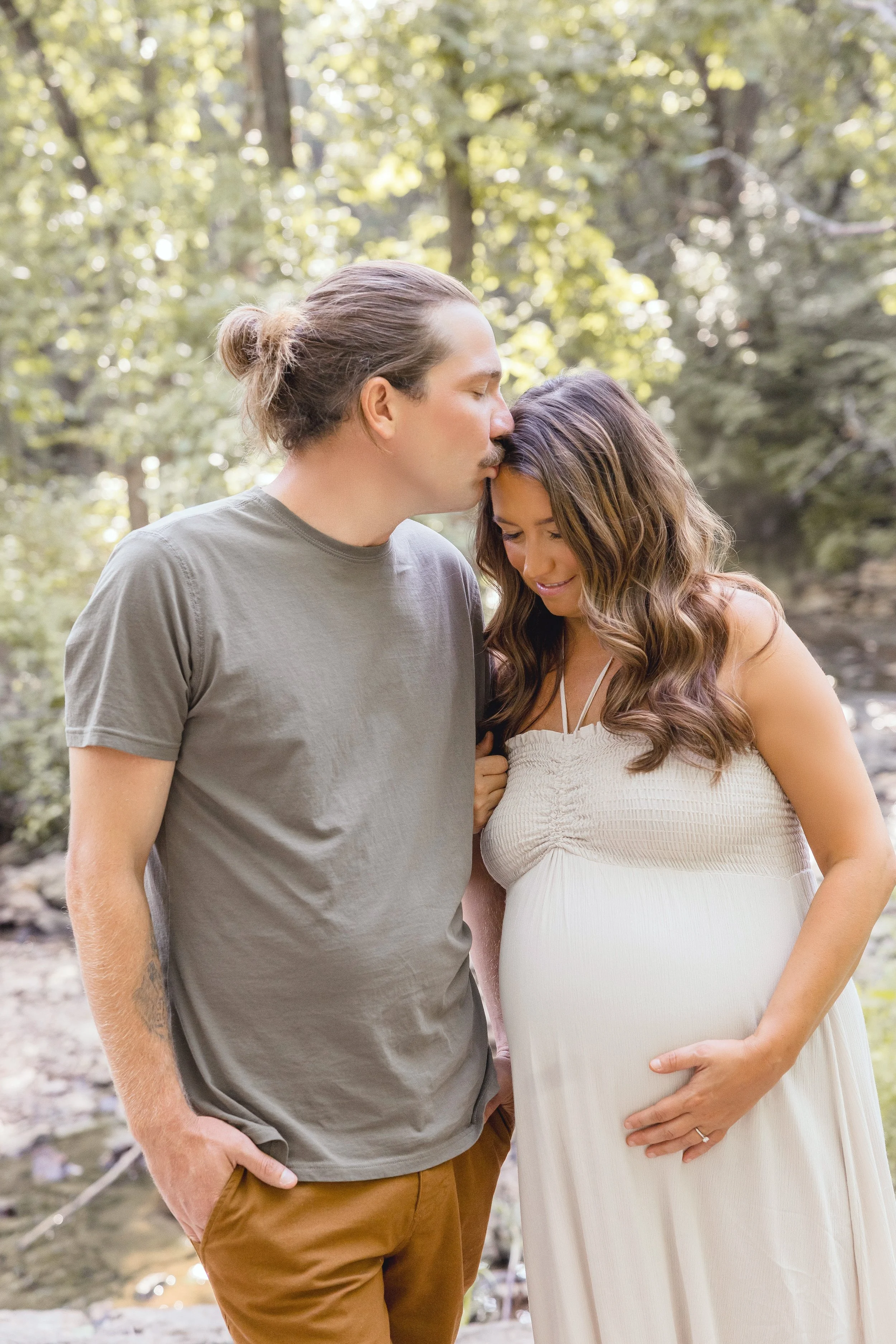 Expecting couple smiling at each other during maternity session in Kansas City, Shawnee Mission Park