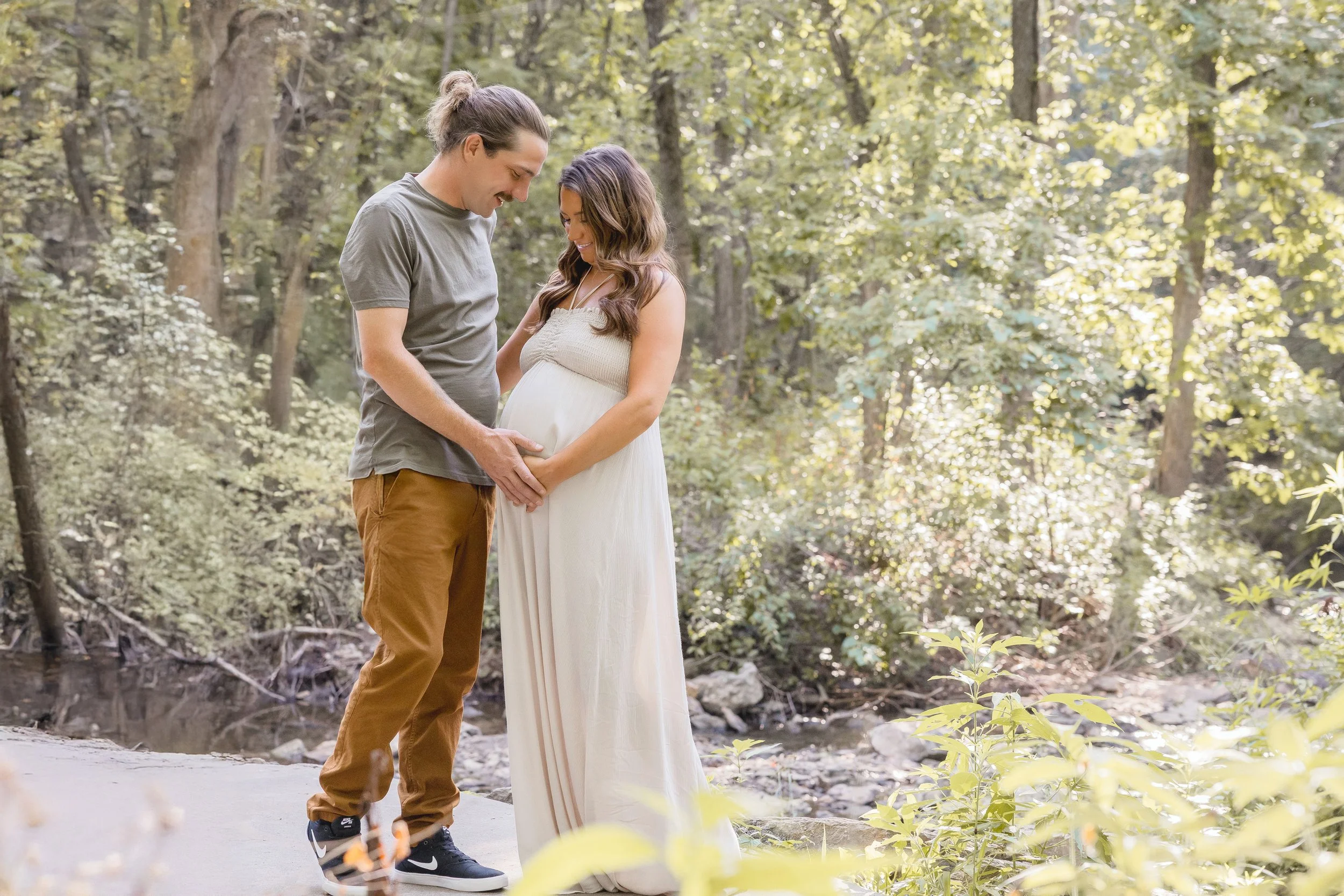 Kansas City maternity portraits, expecting couple smiling during golden summer evening