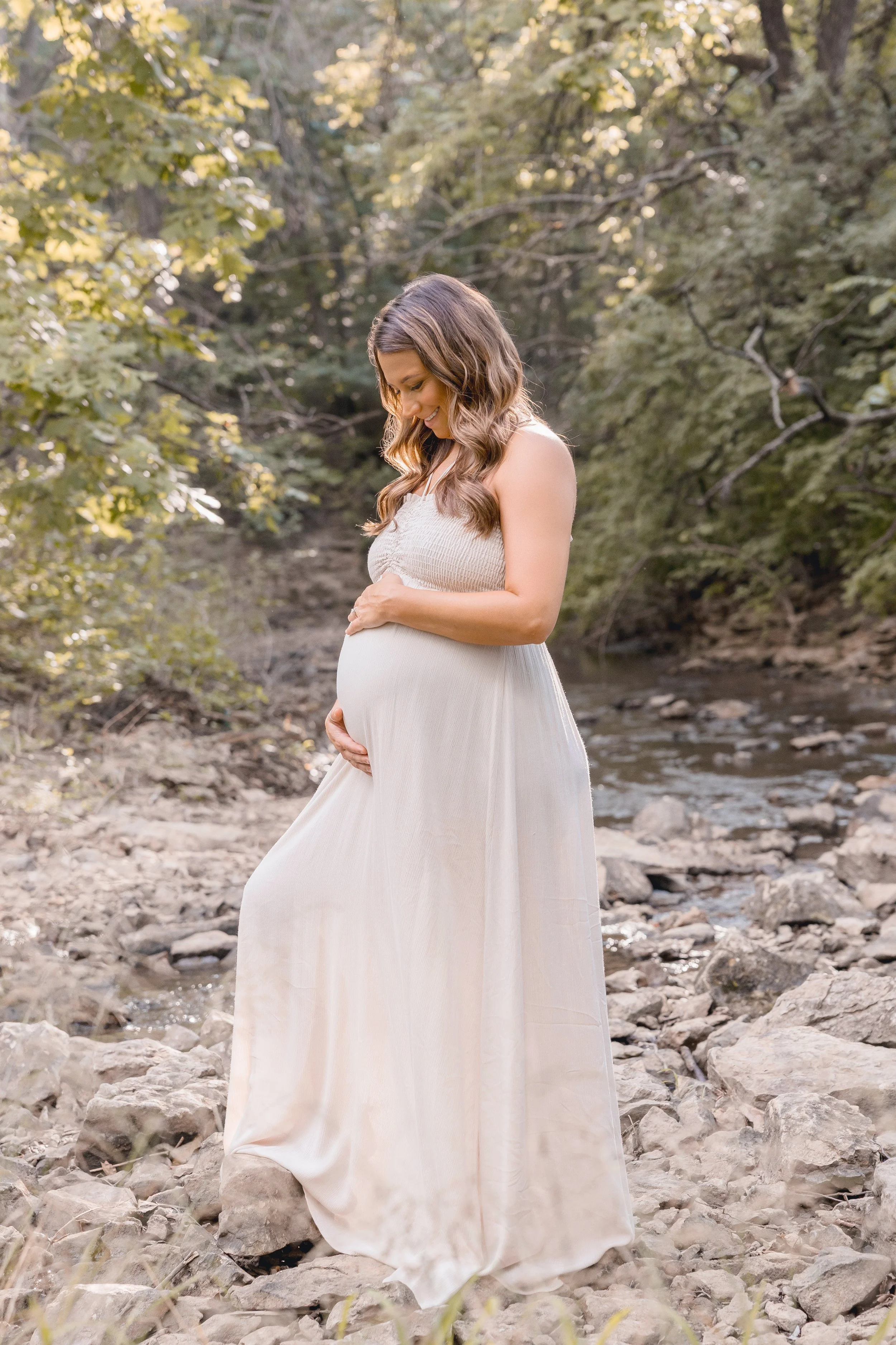 Solo maternity portrait in Kansas City, expecting mother in soft gown with golden evening light