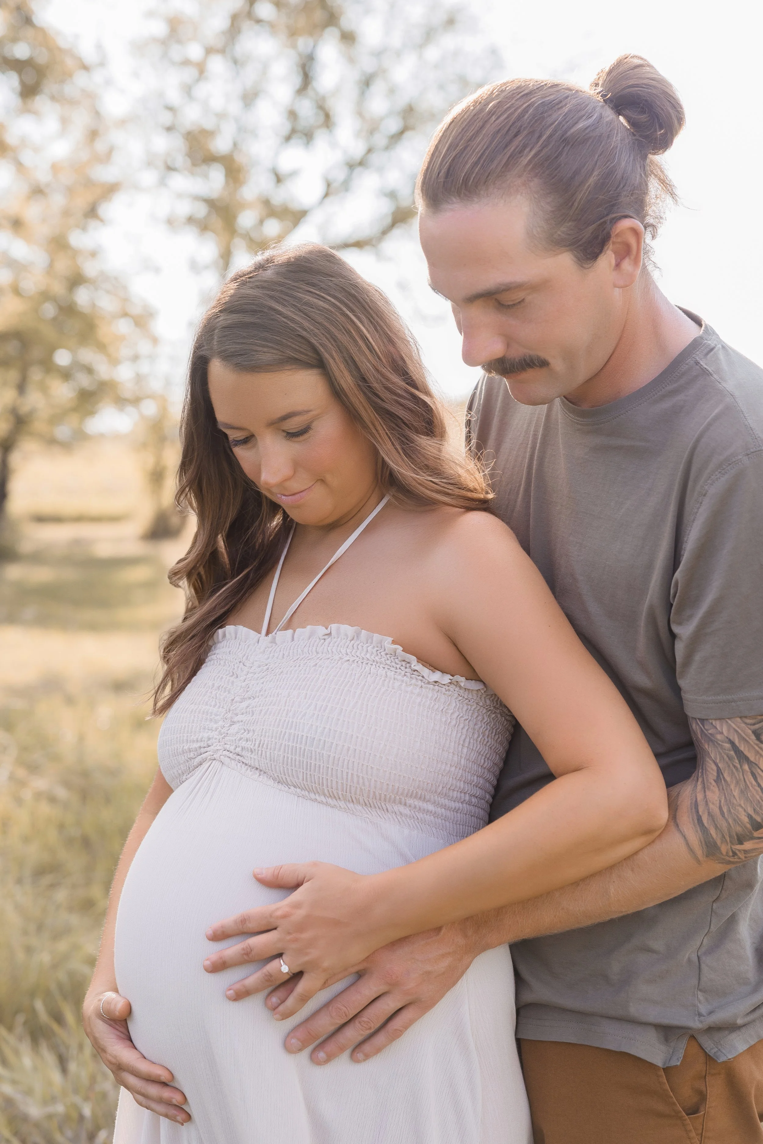 Expecting couple embracing during a summer maternity session at Shawnee Mission Park in Kansas City
