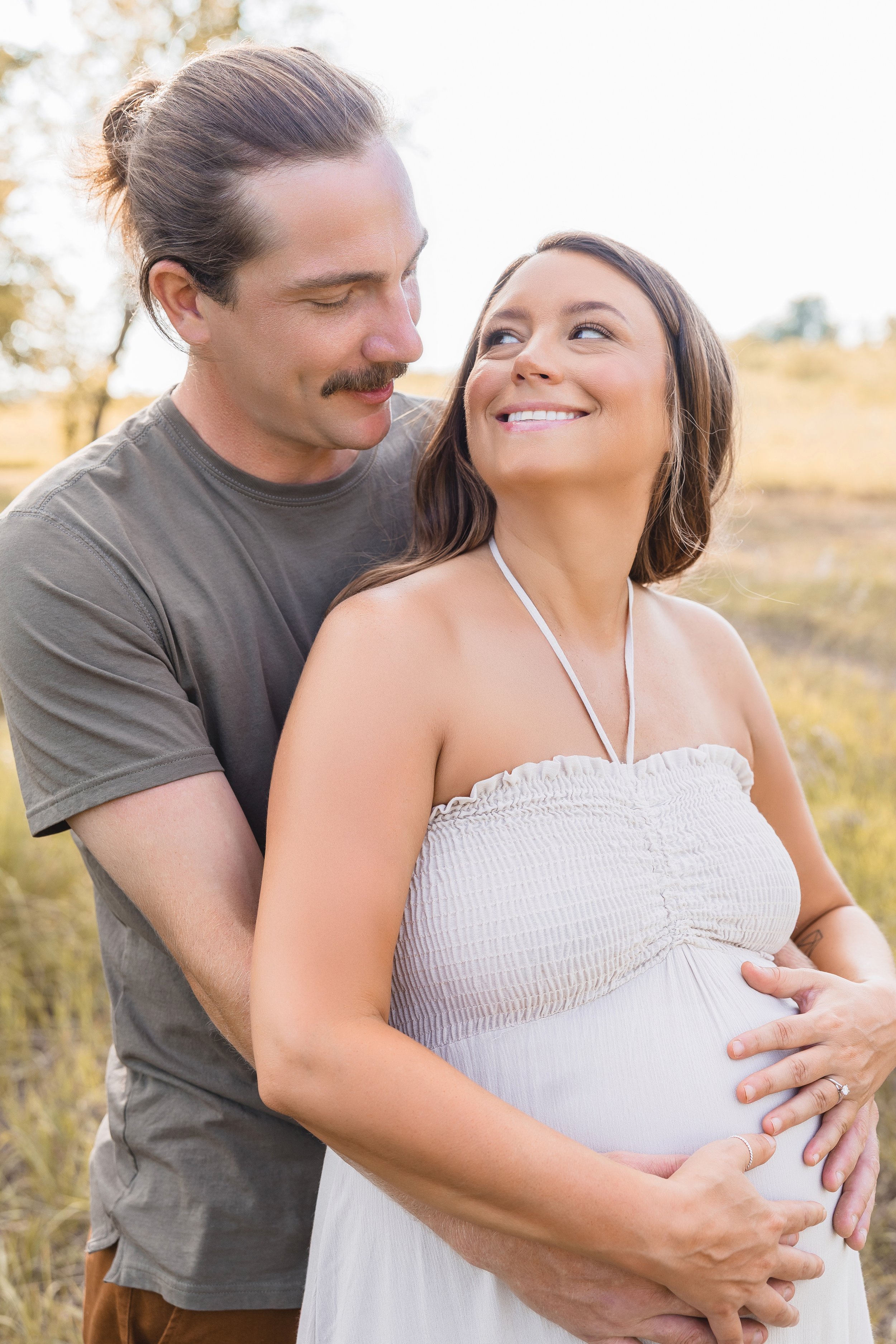 Maternity portraits in Kansas City, couple smiling together during golden summer light at Shawnee Mission Park