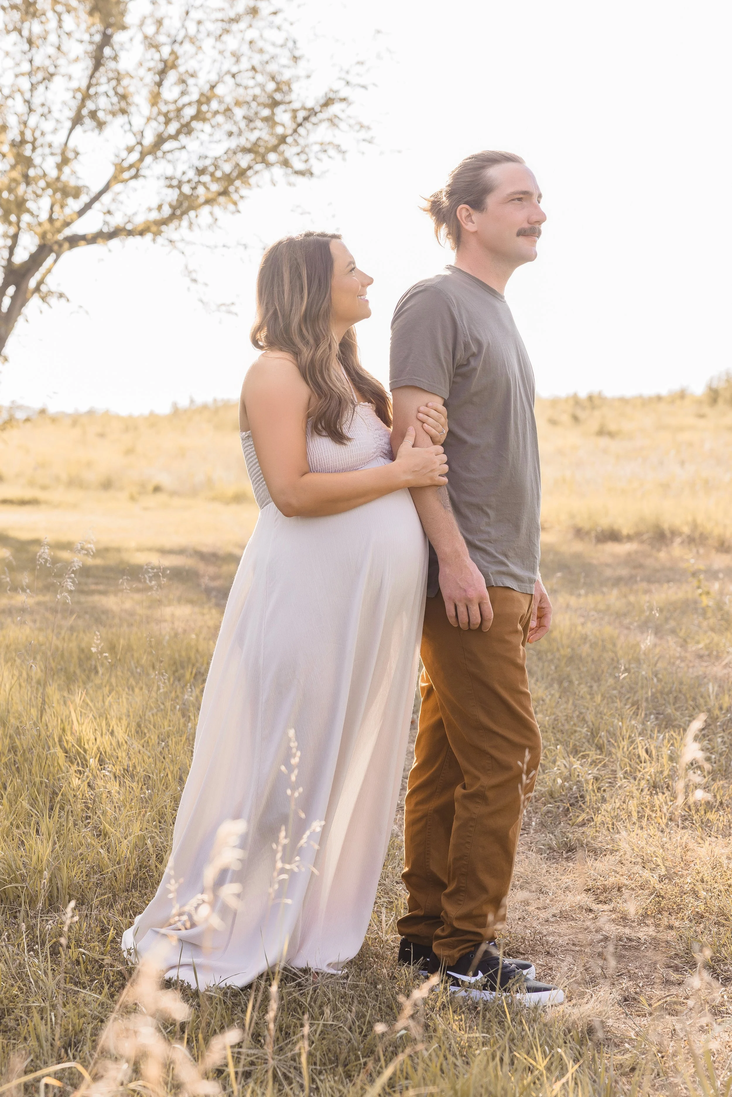 Expecting couple standing together in soft light at Shawnee Mission Park in Kansas City