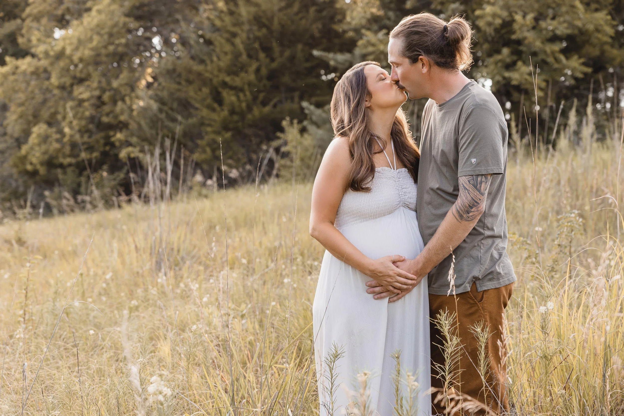 Maternity portraits in Kansas City, expecting couple walking through tall grass at sunset