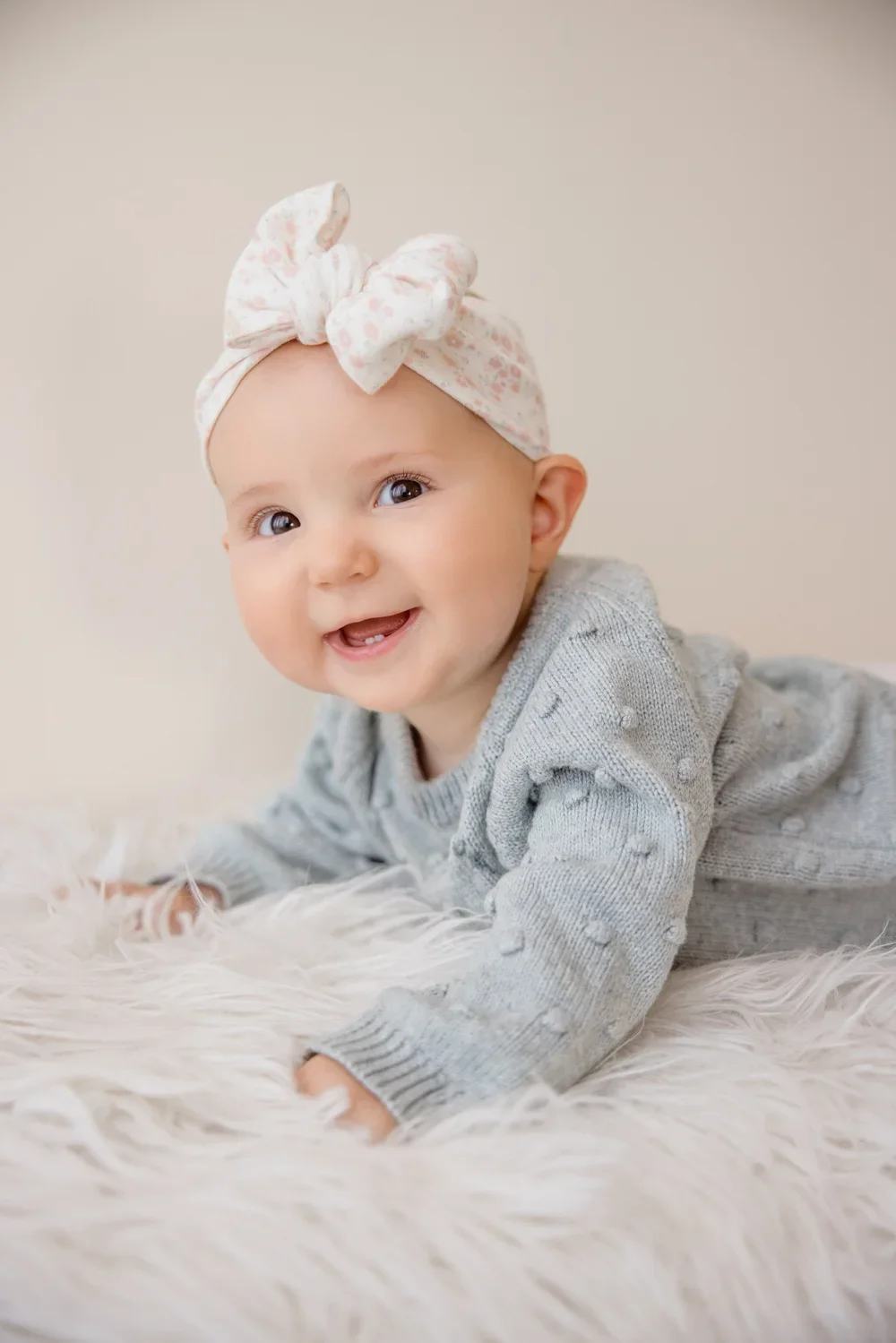 Nine month baby milestone photography session in Kansas City natural light studio featuring baby in cozy neutral outfit.