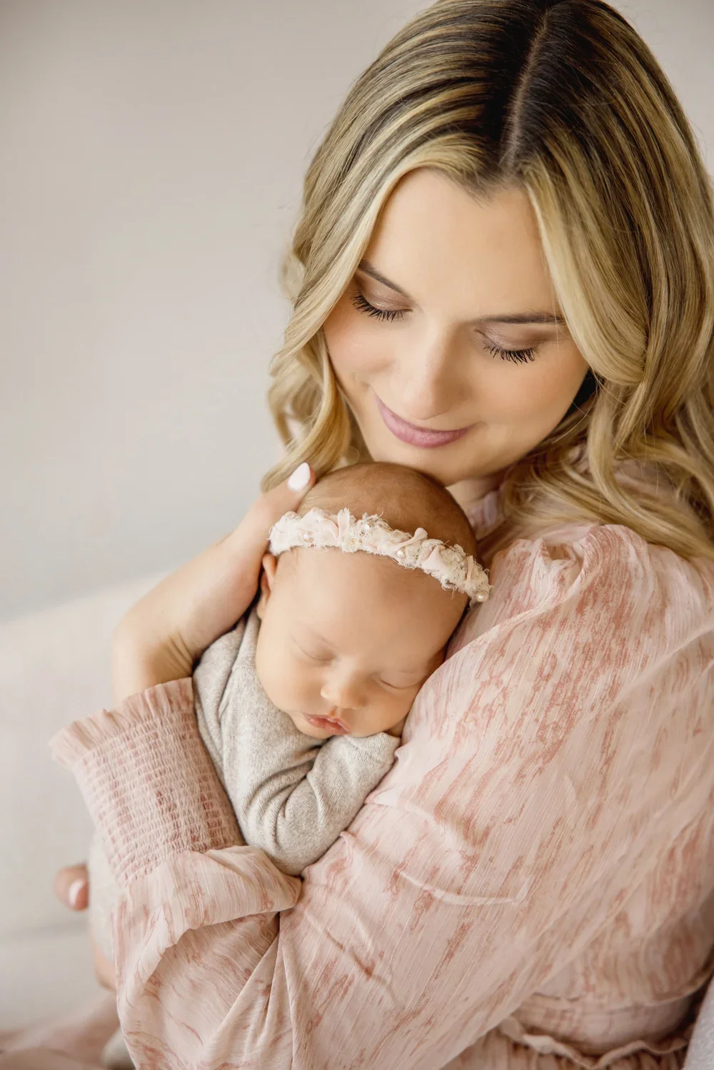 Kansas City newborn photography session in a natural light West Bottoms studio with mother holding her baby in soft neutral tones.