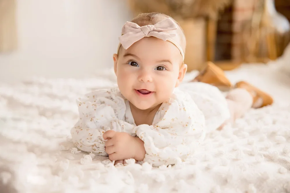 Three month baby milestone photography session in Kansas City studio with baby smiling on a soft white blanket.