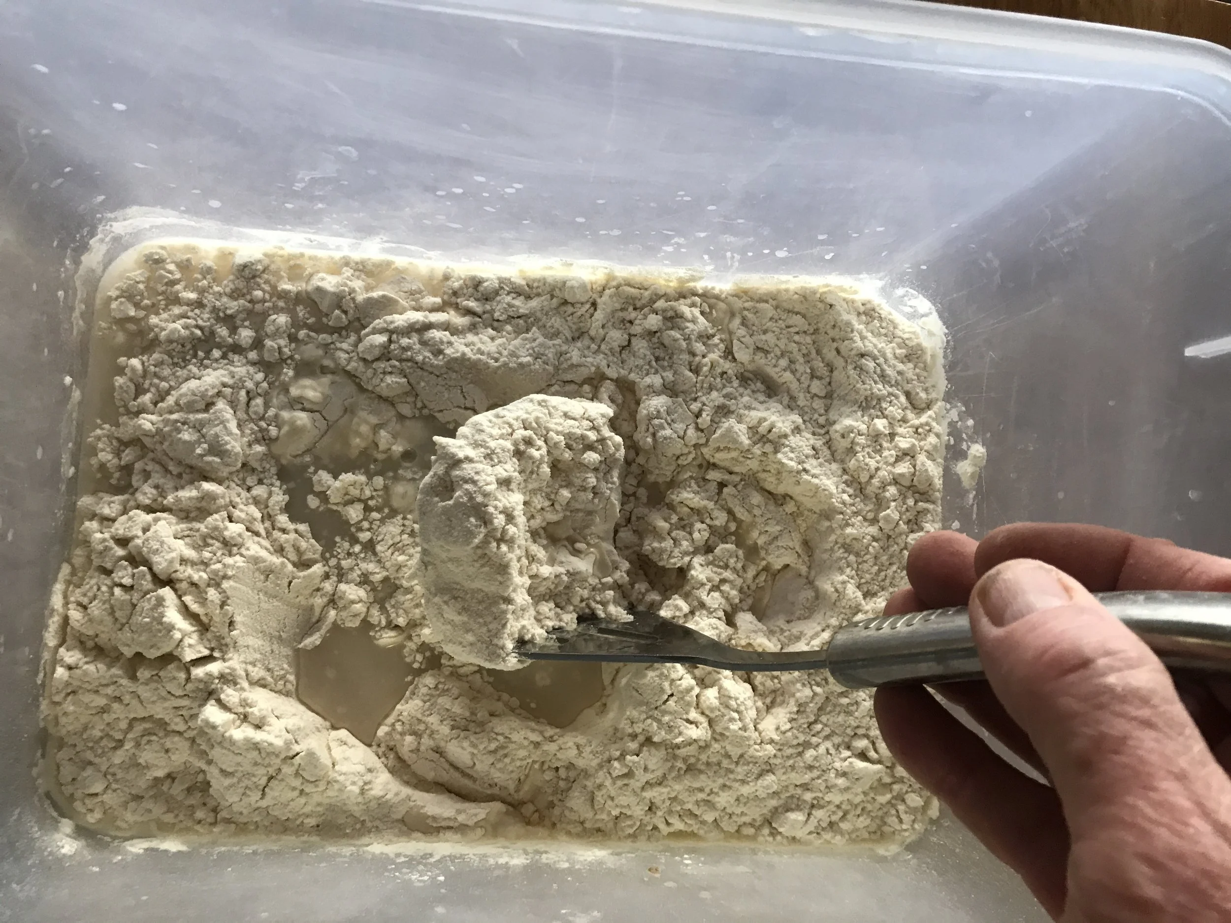 Using a potato masher to mix the sponge.