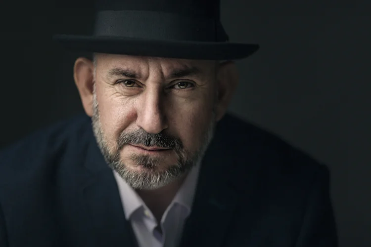 Man in a black fedora and dark suit, studio portrait