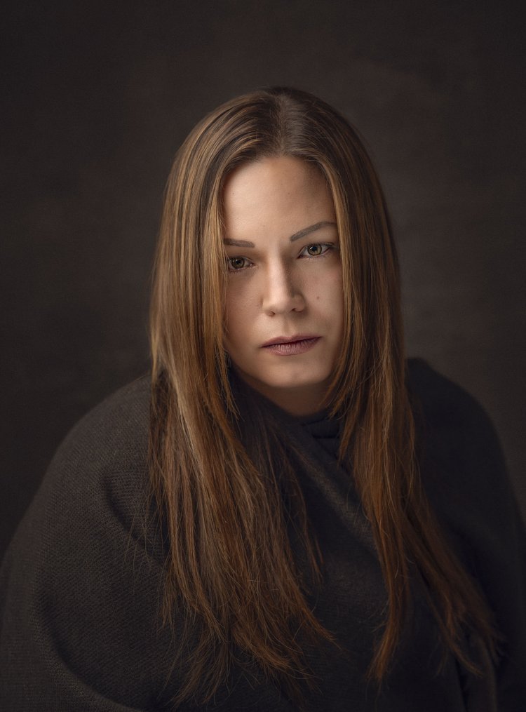 Woman with long auburn hair against a dark backdrop