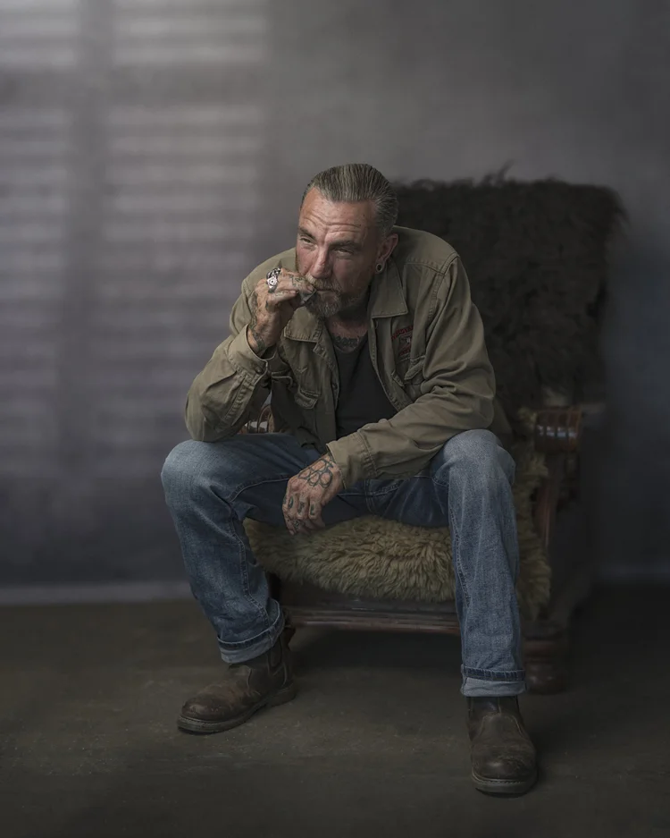 Man in a jacket sitting in a fur-draped armchair