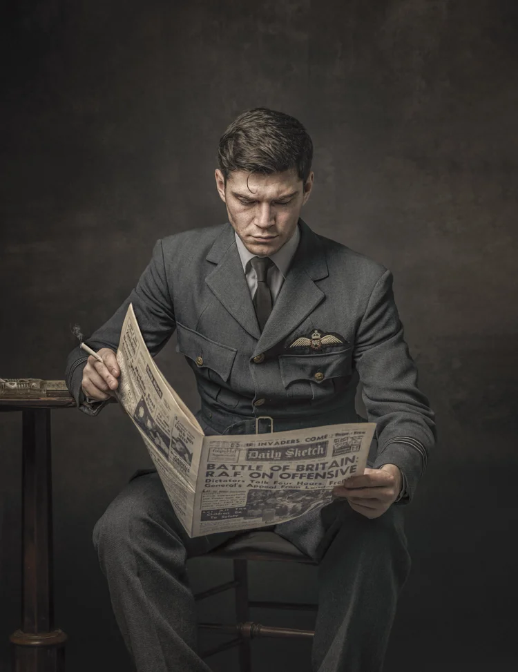 Young man in a 1940s RAF uniform reading a newspaper