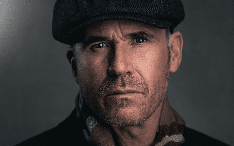Close-up portrait of a man in a flat cap, cinematic lighting