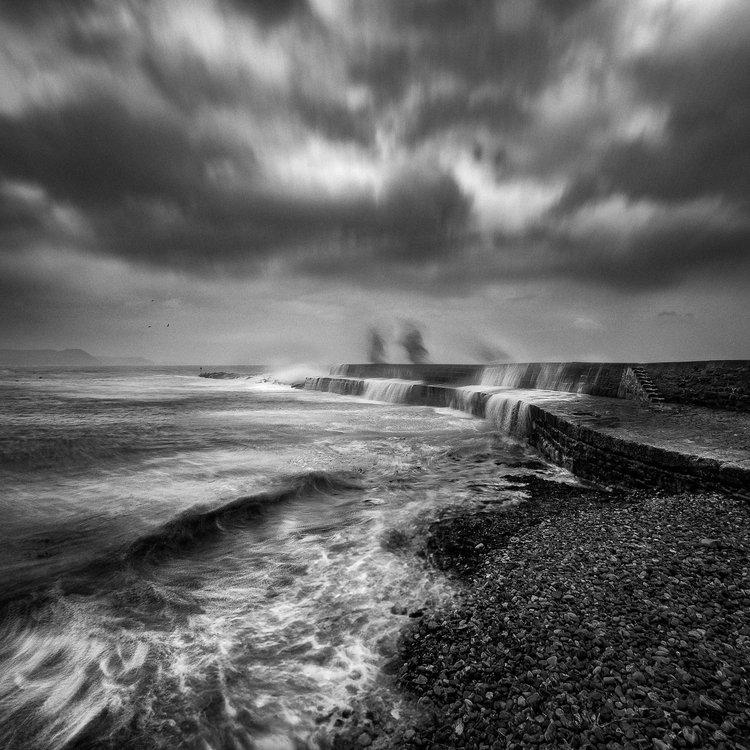Black and white image of stormy waves against the sea wall at Lyme Regis
