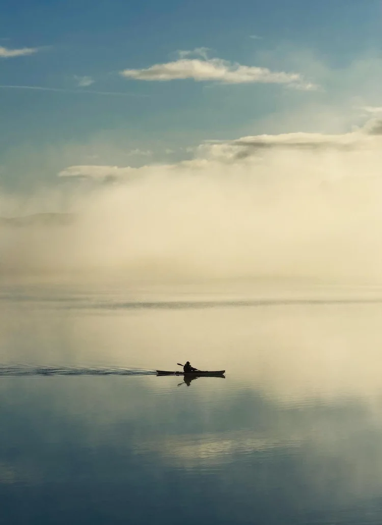 Lone paddler on calm water under a soft sky in Wales