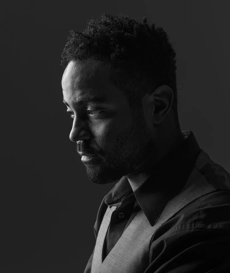 Low-key profile portrait of a man in a shirt and jumper