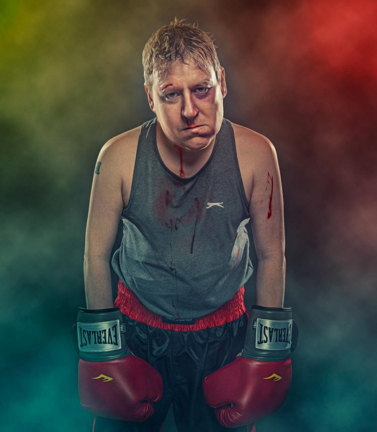 Boxer in red gloves with a bruised face against coloured smoke