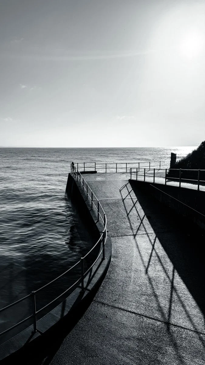 Black and white image of a walkway leading out to sea at Lyme Regis