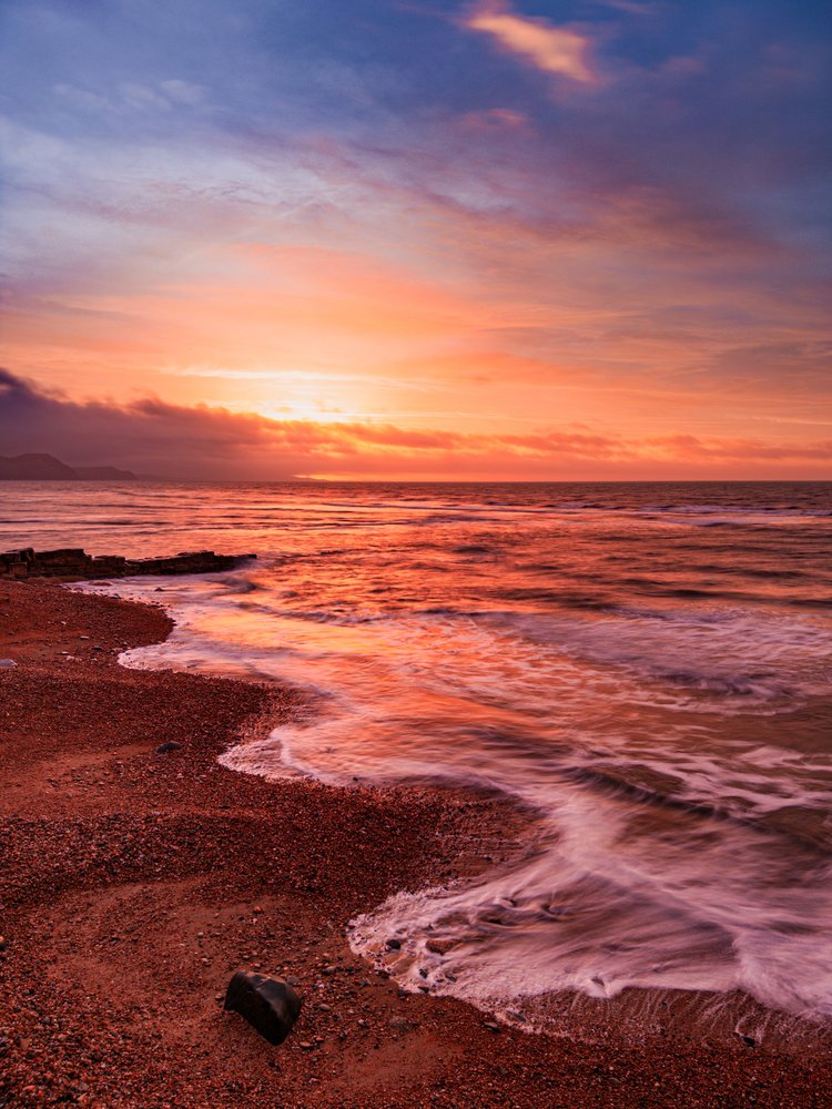 Vivid sunrise over the sea and sand at Lyme Regis