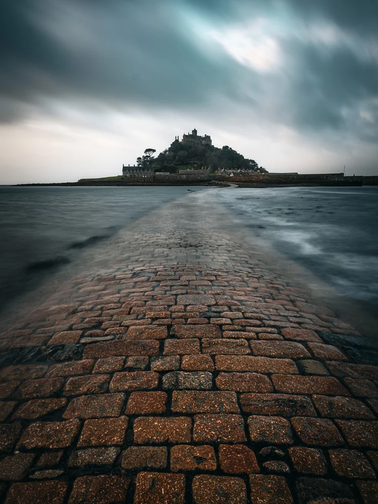 Brick causeway leading across the sand towards an island castle