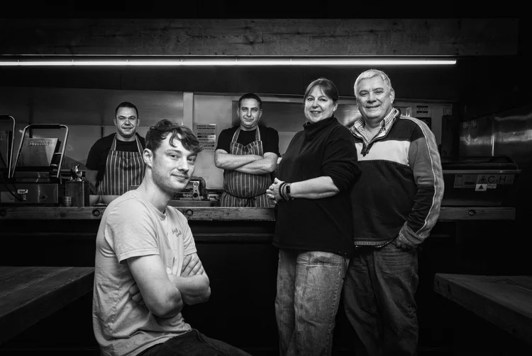 Black and white group portrait of five people inside a working mill