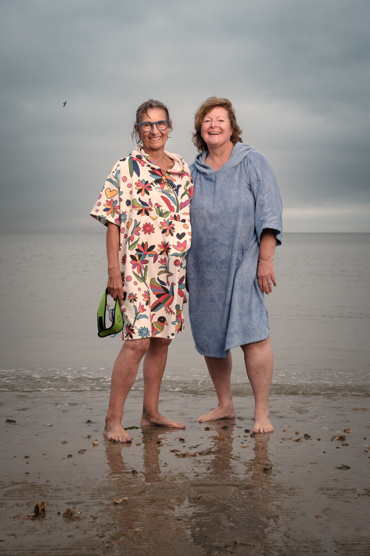 Early morning sea swimmers Mary and Christine standing together in the shallows