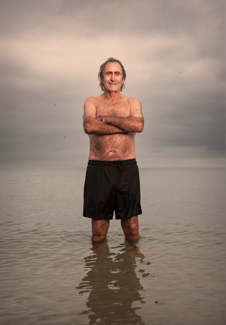 Sea swimmer known locally as Neptune standing with arms folded in the shallows
