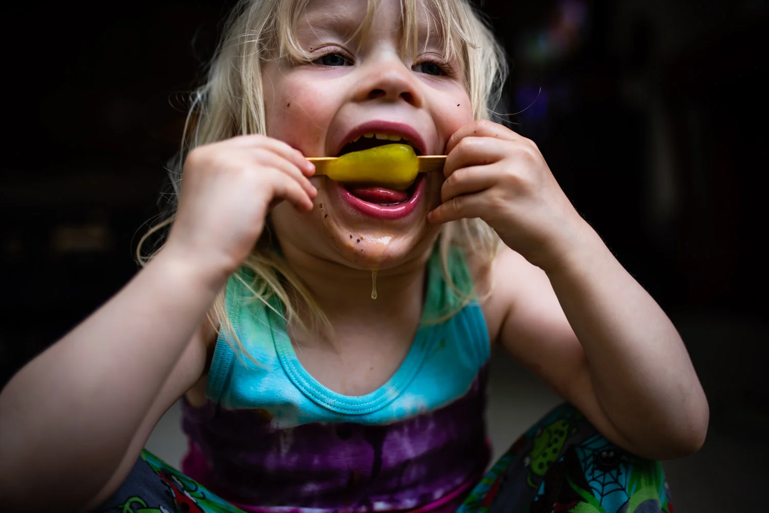 A little toddler boy sits licking an ice lolly during this fun, relaxed, unposed family photo shoot.