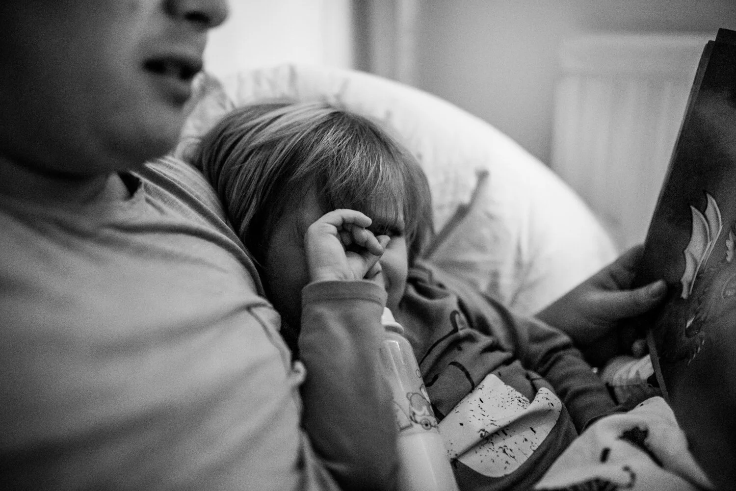 A father reads his son a bedtime story in his sons new bedroom at their home in bath somerset and his son is rubbing his eyes.