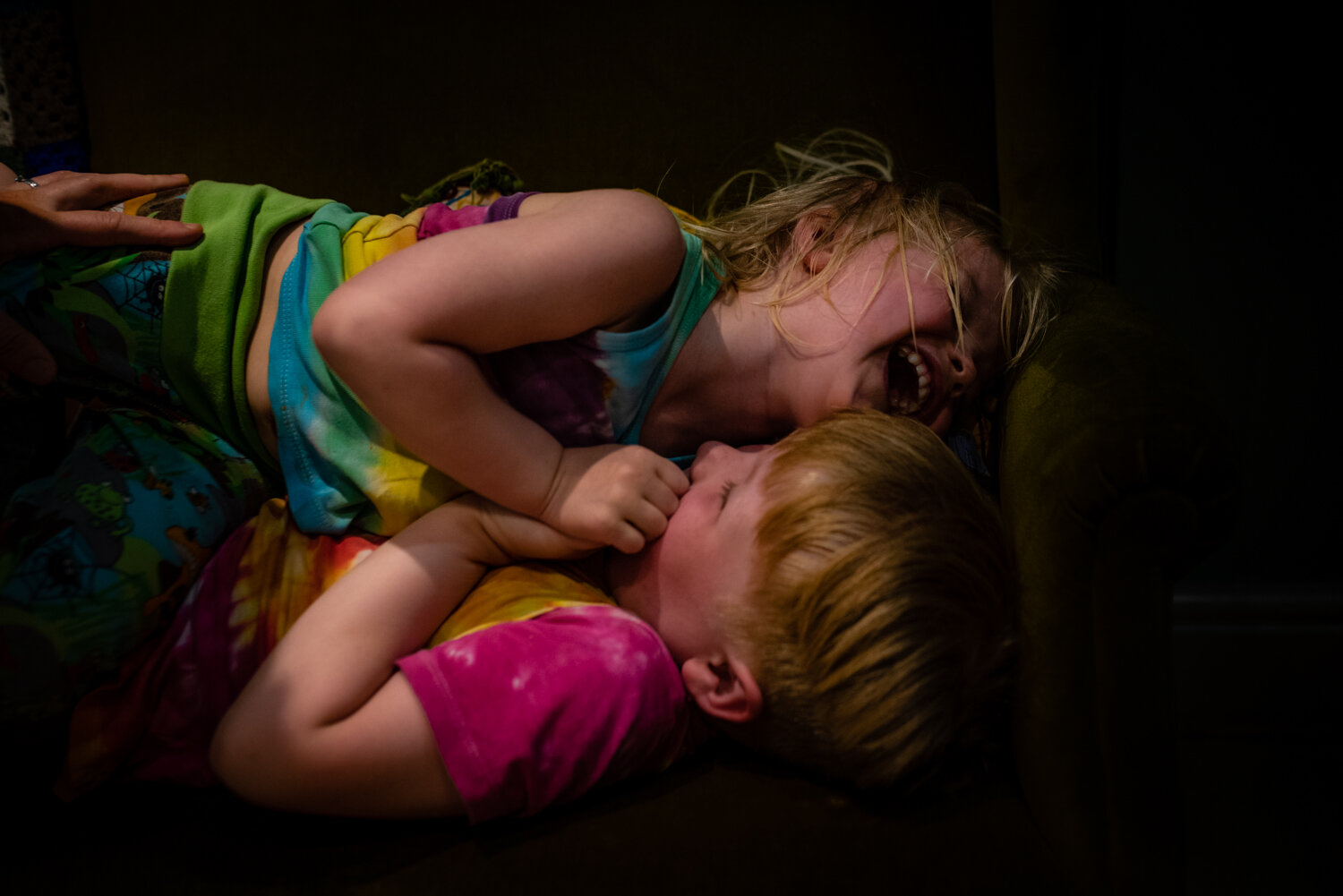  Two brothers lie on their sofa laughing together whilst they are being tickled by their Mum during this fun day in the life documentary family photo shoot in Bristol. 