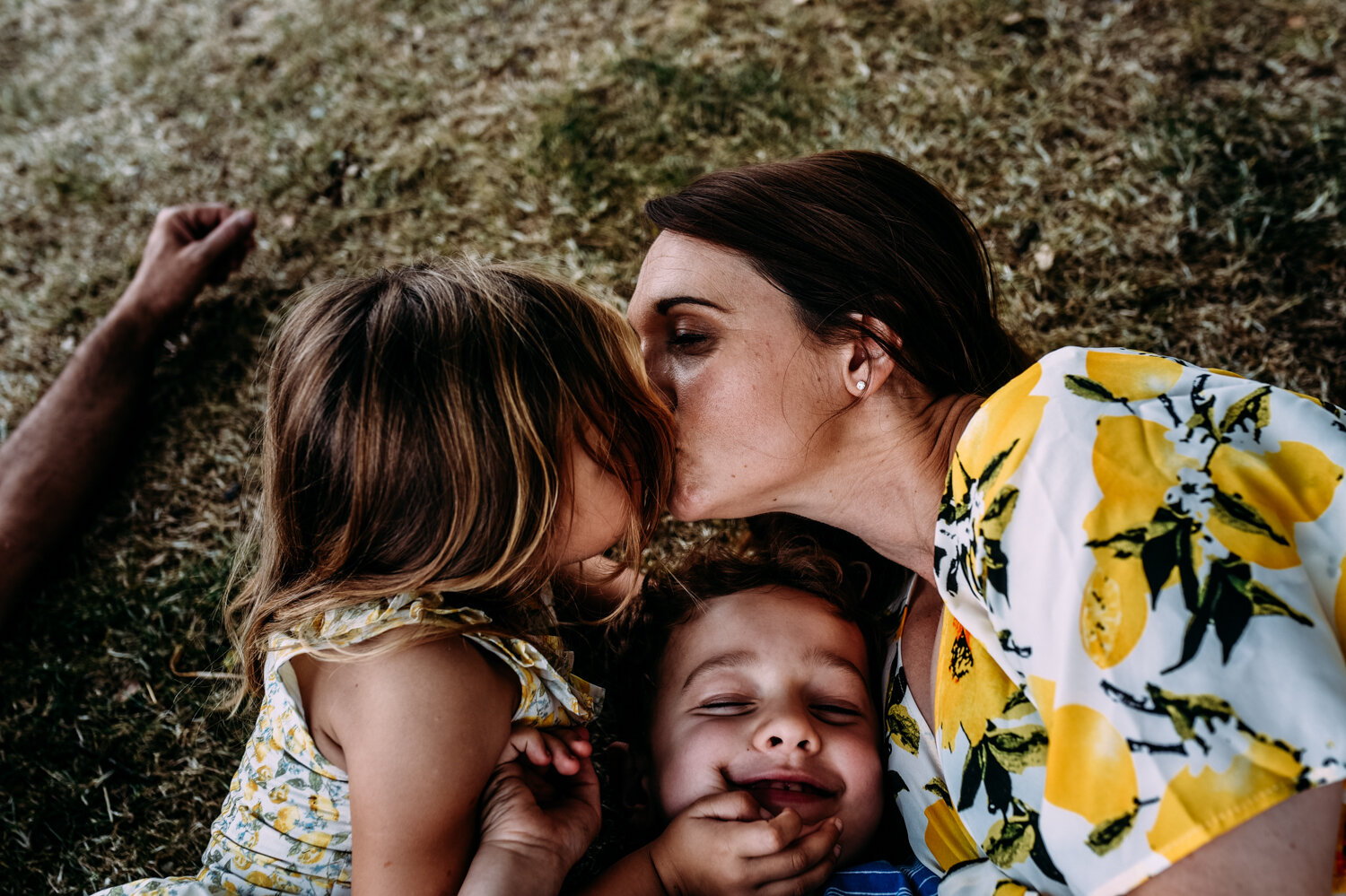  Mother lies on the grass at the Somerset Lavender fields and kisses her daughter. 