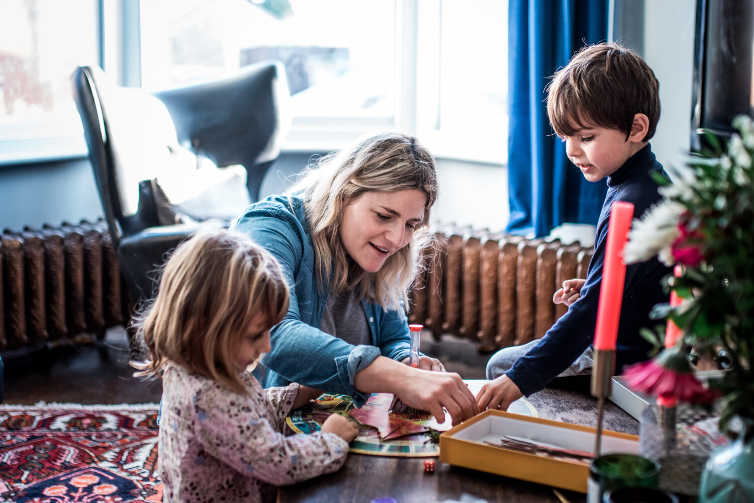  A mother sits on the floor with her children in their living room playing a board game during this relaxed family photo shoot in Bath. 