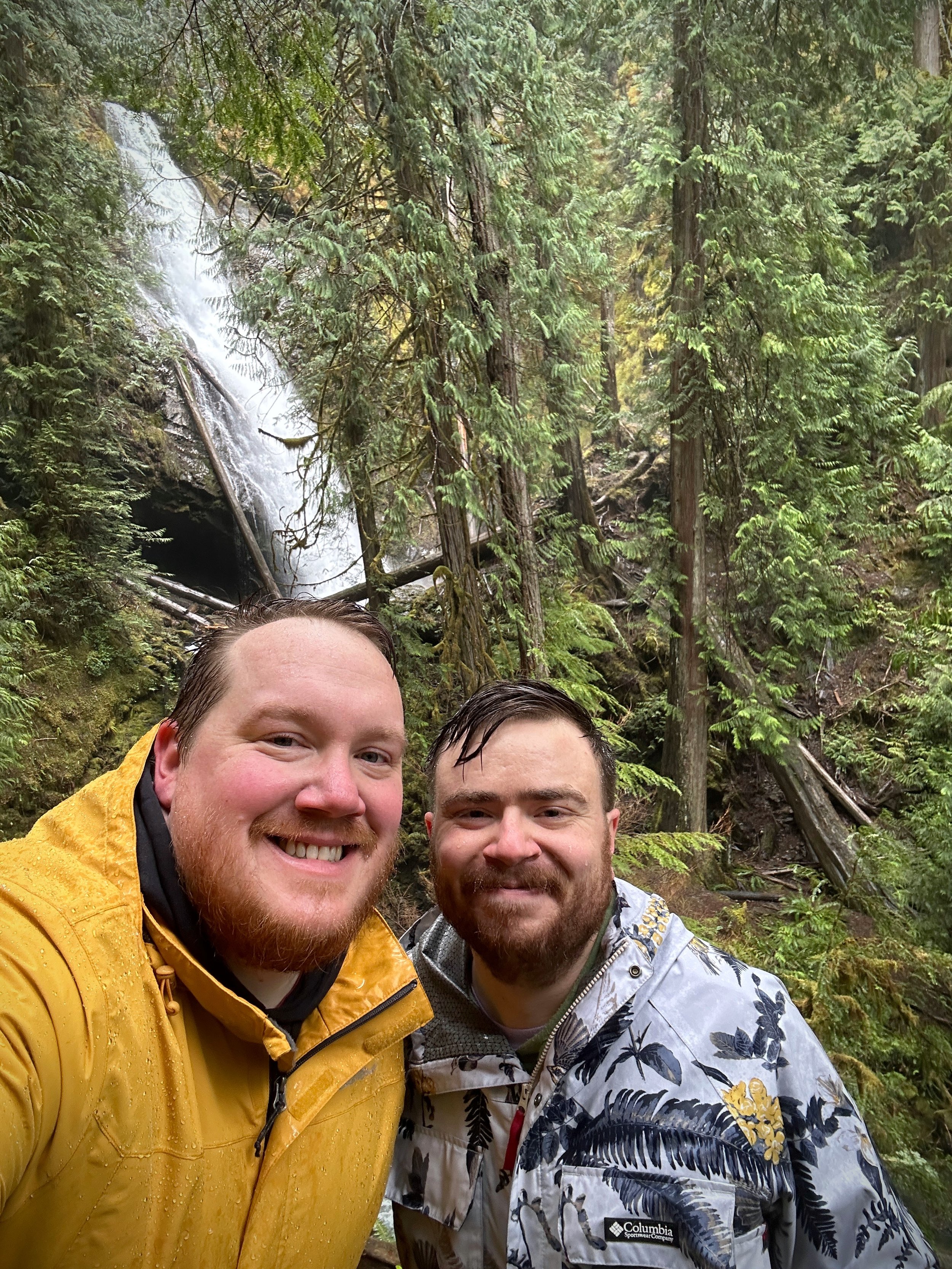 two peple standing in front of a waterfall