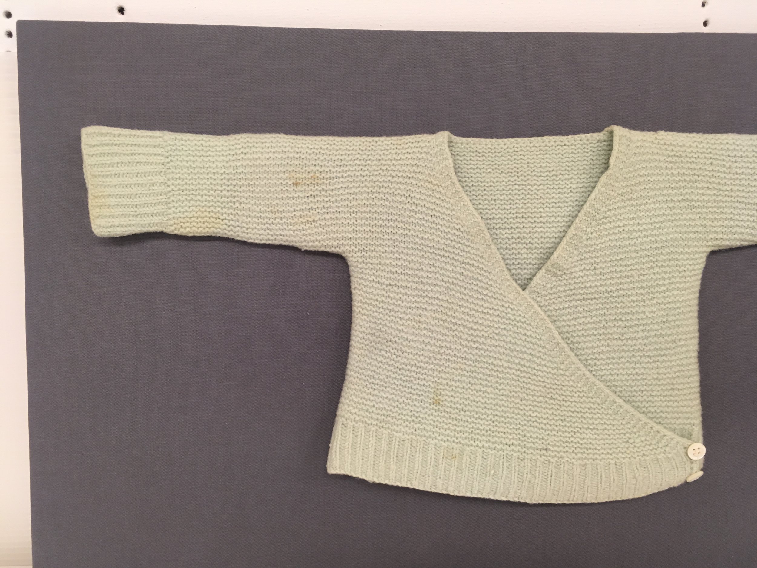 c. 1940 infant sweater on a custom fabric covered slat mount.