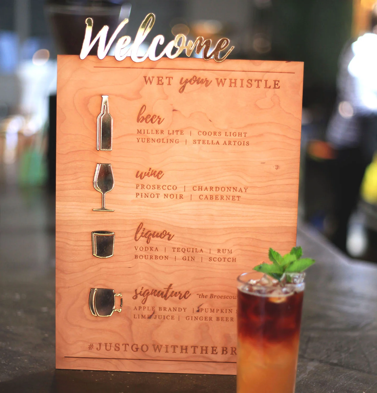 An engraved wood bar sign with eye gold mirror inlaid details for a wedding.