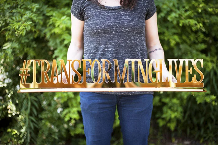 A gold mirror hashtag sign made for a school fundraiser. This sign stands upright on a table top.