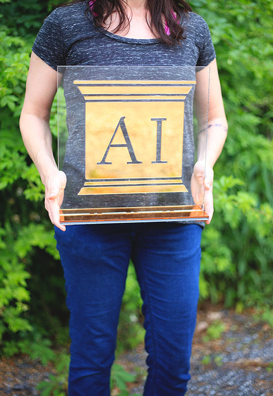 This custom sign is made from gold mirror acrylic and clear acrylic, stands on a table top, and was used for a fundraising event for The Monarch School in Texas.