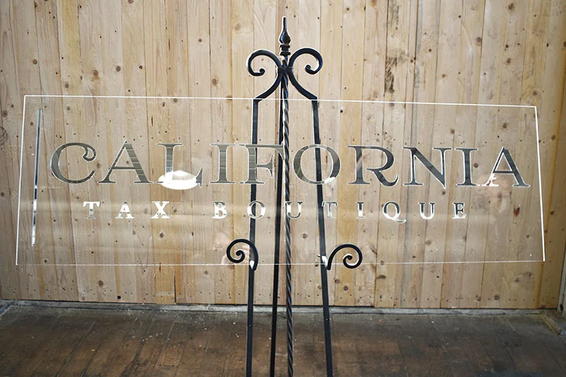A 6 foot long silver mirror business sign mounted onto clear acrylic.