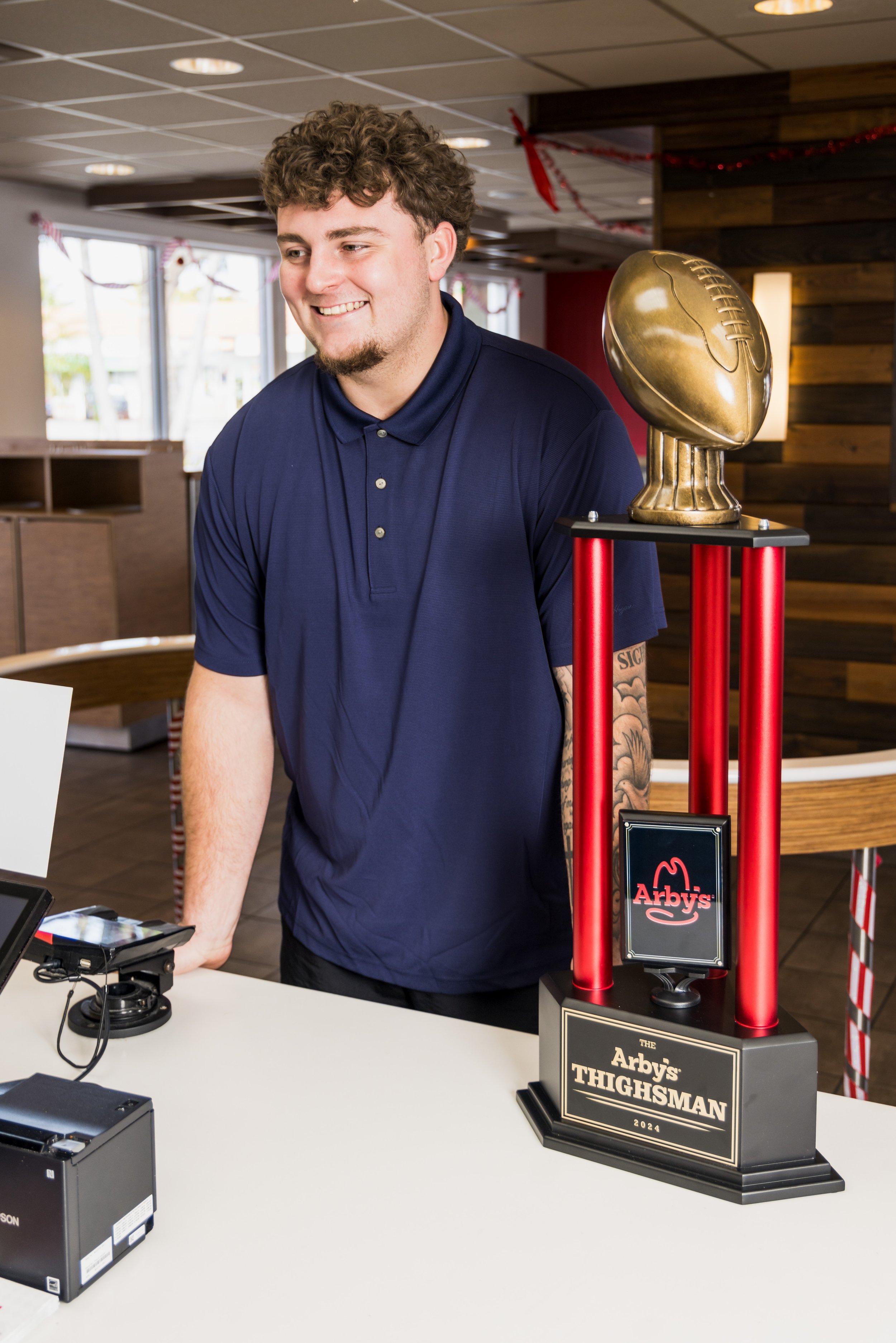 Mason Graham orders at an Arby's counter with the Arby's Thighsman Award next to him