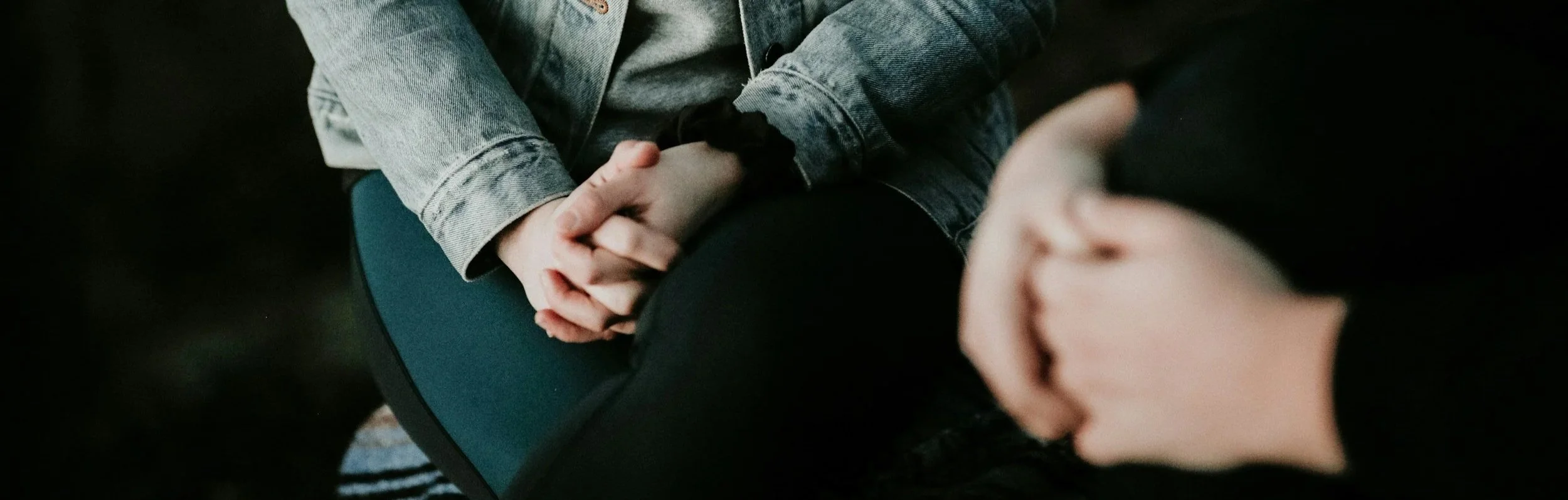Hands in laps of two women sitting 90º to each other