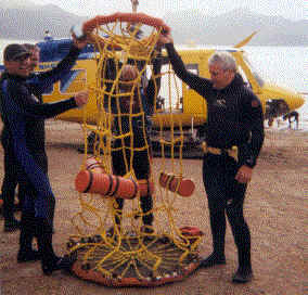Tim Coates, Andy Martinez and John Jackson hold up the Billy Pugh used to recover divers and transport them over short distances to shore. Using this device is less time consuming than a mechanical hoist. The team also trains using the hoist when it is available.