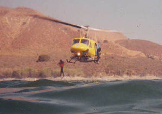 A crew chief inside the helo signals divers to egress the craft. It is important for both the divers to go at the same time so the helicopter doesn't experience a dramatic weight shift. On this training jump, the divers timing was off.